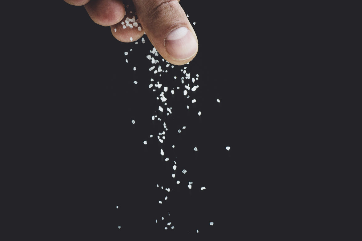 Main qui fait tomber des grains de sel